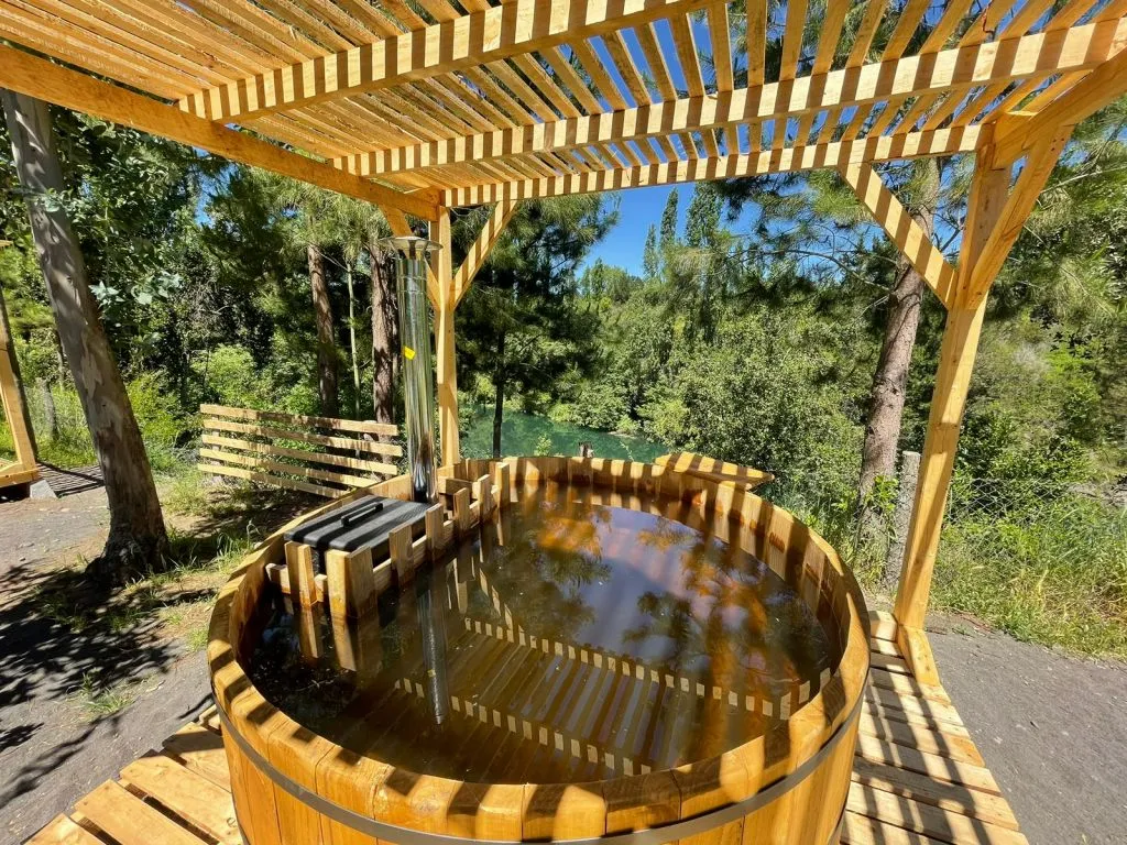 Mesa de ping pong bajo pérgola con piscina y reposeras al fondo